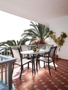una mesa y sillas en un balcón con una palmera en El Nido, en Almuñécar