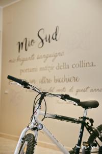 Una bicicleta estacionada frente a una pared con escritura. en Mio Sud, en Cosenza
