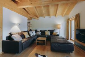a living room with a black leather couch and a tv at Apart-Hotel Laurus Lech in Lech am Arlberg