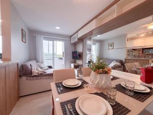 a kitchen and living room with a table and a living room at Apê com A/C, Garagem e Piscina em Canasvieiras in Florianópolis