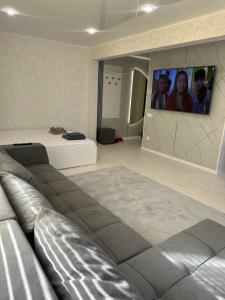 ein Wohnzimmer mit einer Couch und einem Fernseher an der Wand in der Unterkunft Квартира 1,5 Евро-люкс in Öskemen + 3 Fotos