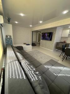 eine große Couch in einem Wohnzimmer mit einem Fernseher in der Unterkunft Квартира 1,5 Евро-люкс in Öskemen