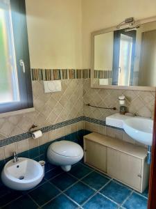a bathroom with a toilet and a sink and a mirror at Villa Baia Verde in Marina di Modica