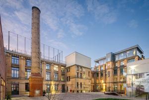a factory with a tall chimney and a building at fabrik studio apartments in Chemnitz +9 photos