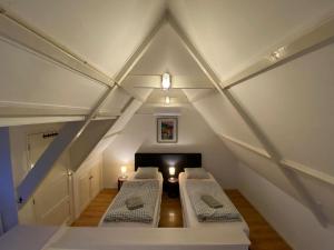 a attic with two beds in a room at BenBZuiderzee in Hattem