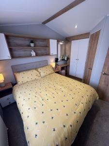 a bedroom with a bed with a yellow comforter at Fantasy Island - Eastgate E5 - The Sierra with Hot Tub - Coastal Caravan Breaks in Ingoldmells +2 photos