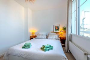 ein Schlafzimmer mit einem weißen Bett mit zwei grünen Handtüchern darauf in der Unterkunft Ker Anna, 120m De La Plage, Vue Mer in La Terre du Pont