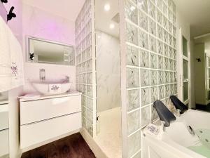 a bathroom with a sink and a toilet and a tub at Les Suites Bisous Metz - Jacuzzi & Private Sauna in Metz