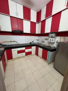 Eine Küche mit roten und weißen Schränken und Fliesenboden in der Unterkunft Awaraj Home Stay in Agra + 1 Foto
