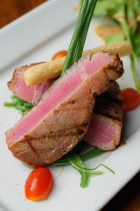 a piece of meat on a white plate with vegetables at Oceanview Bungalows by EAT in Karon Beach