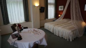 pokój hotelowy z łóżkiem i białym stołem w obiekcie Hotel het Gemeentehuis Uithuizen w mieście Uithuizen