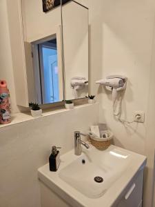 a white bathroom with a sink and a mirror at Appartement diamant in Brussels +1 photo