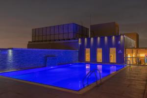 a swimming pool with blue lighting in front of a building at The Grand Lux Hotel in Doha