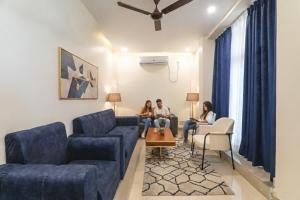 three people sitting on a couch in a living room at FabHotel Raj Palace in Lucknow