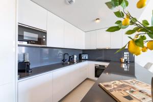 ラ・カラ・デ・ミハスにあるLuxury 2BD Flat - Pools - Parking - Spa - Gymのキッチン(白いキャビネット、黒いカウンタートップ付)