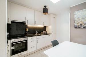 a kitchen with white cabinets and a sink at Terrazza Paradiso by Quokka 360 - Spacious Design Flat with Terrace in Paradiso