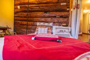 1 dormitorio con cama roja y pared de madera en Bel appartement confortable et lumineux Molines en Queyras - Saint Véran, en Molines-en-Queyras