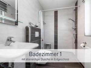 ein weißes Badezimmer mit Waschbecken und Dusche in der Unterkunft Komfortables Ferienhaus Strandzauber auf Fehmarn für 8 Personen mit 4 Schlafzimmern und 2 Bädern in Fehmarn