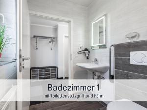 ein weißes Badezimmer mit Waschbecken und Spiegel in der Unterkunft Komfortables Ferienhaus Strandzauber auf Fehmarn für 8 Personen mit 4 Schlafzimmern und 2 Bädern in Fehmarn