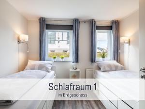 zwei Betten in einem Zimmer mit zwei Fenstern in der Unterkunft Komfortables Ferienhaus Strandzauber auf Fehmarn für 8 Personen mit 4 Schlafzimmern und 2 Bädern in Fehmarn