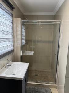 Un baño con ducha de cristal y lavabo. en Marikana guest house, 