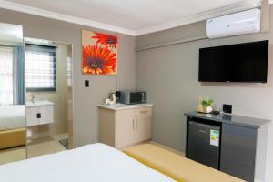 Una habitación de hotel con una cama y un televisor de pantalla plana. en Marikana guest house, 