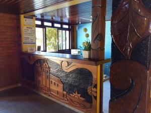 a wooden counter with a painting of a building at Pousada Portal da Barra in Marataizes