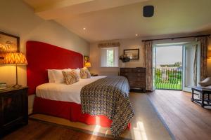 a bedroom with a large bed with a red headboard at The Bay Tree Hotel in Burford