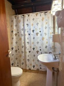 a bathroom with a shower curtain with a toilet and a sink at Cabañas Pindahue - Alojamineto Epehuen in Villa Carlos Paz