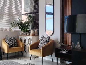 a living room with two chairs and a television at Santos 24 in Mossel Bay