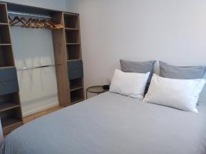 a bedroom with a bed with white pillows and a closet at Vkls Appartement 1 in Languidic