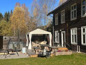 a gazebo on a deck next to a house at Nord-Garthus gård leilighet 1 in Hølera