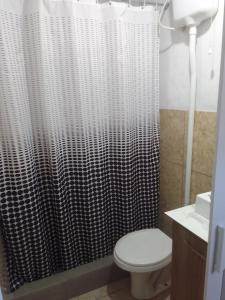 a bathroom with a toilet and a shower curtain at Estúdio em Capão da Canoa in Capão da Canoa +14 photos