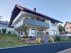 a white house with flowers on the balcony at Ferienwohnung Familie Aestel in Altensteig