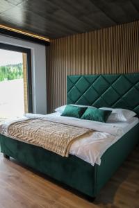 a bedroom with a large bed with a green headboard at Chata Andromeda in Oravská Lesná