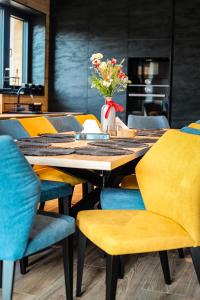 a table with yellow chairs and a vase with flowers at Chata Andromeda in Oravská Lesná