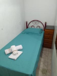 a blue bed with two towels and a dresser at Estúdio em Capão da Canoa in Capão da Canoa
