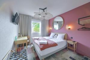 a bedroom with a bed with a pink wall at BHOMA Bourges - Hôtel in Bourges