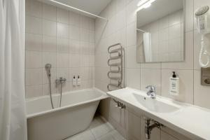 a white bathroom with a sink and a bath tub at RIJA Riga City Centre Hotel in Riga