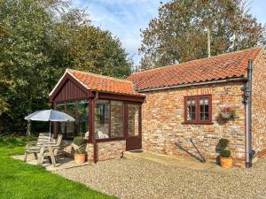 una pequeña casa de ladrillo con sombrilla y mesa en The Old Chapel, en Burshill