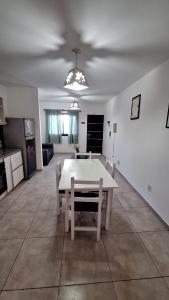 un salon avec une table et des chaises blanches dans l'établissement Departamento a metros del Shopping, à Guaymallen