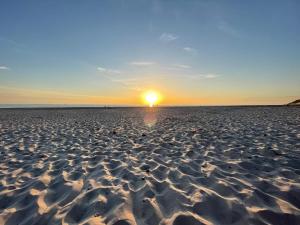 a beach with the sun setting on the horizon at 6 person holiday home in Hvide Sande-By Traum in Hvide Sande