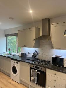 a kitchen with a stove top oven next to a dishwasher at Cosy 2 Bed Maisonette near Heathrow & Windsor in Staines