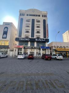a large building with cars parked in a parking lot at AL-salam suites in Salalah