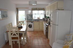 eine Küche mit einem Tisch und einem weißen Kühlschrank in der Unterkunft 32 Benbane Park in Portballintrae