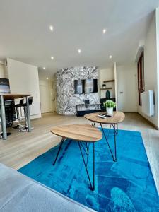 a living room with two tables and a blue rug at Le cœur des princes in Montbéliard +16 photos