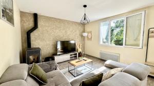 un salon avec un canapé et une télévision dans l'établissement Le refuge, Wifi, Parking privé, Proche Limoges, terrasse, jardin, à Le Palais-sur-Vienne