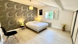 - une chambre avec un lit, une chaise et un mur dans l'établissement Le refuge, Wifi, Parking privé, Proche Limoges, terrasse, jardin, à Le Palais-sur-Vienne