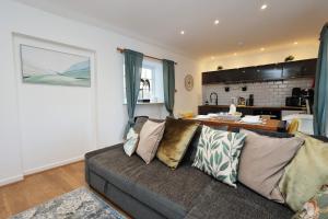 a living room with a couch and a kitchen at Little Gem in the Forest of Dean! Hot tub, Private garden, Dog Friendly, Smart TVs and Beautiful Historic Village Location! in Saint Briavels