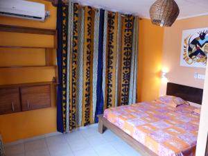 a bedroom with a bed and some curtains at Villa Charlestine in Yaoundé